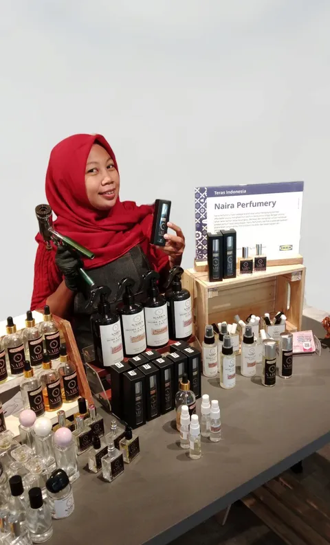 Nadira Ayu Larasati di samping rak botol parfum Naira Perfumery