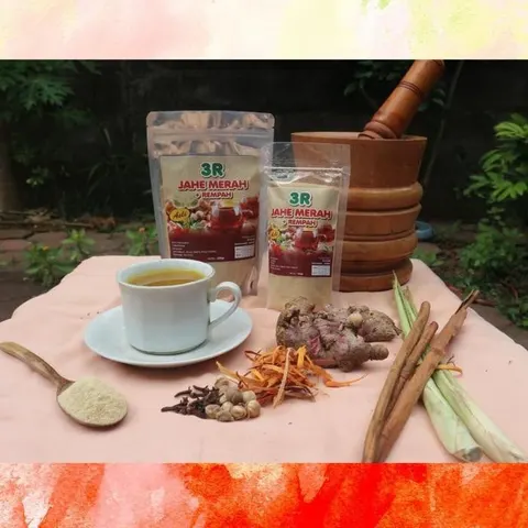 Dua kemasan 3R Jahe Merah + Rempah, secangkir minuman, jahe merah, kayu manis, serai dan cengkih di atas kain