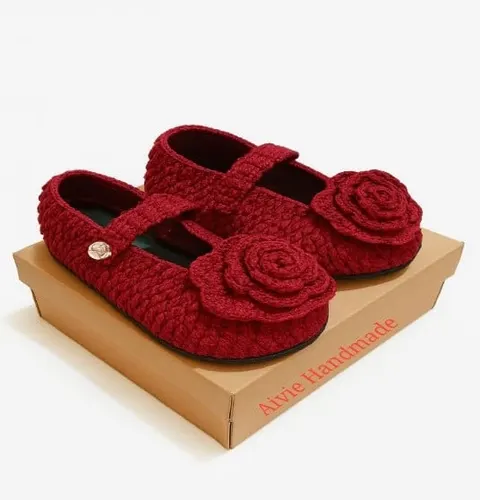 Sepasang sepatu rajut merah berhias bunga mawar rajut di atas kotak kraft bertulisan Aivie Handmade