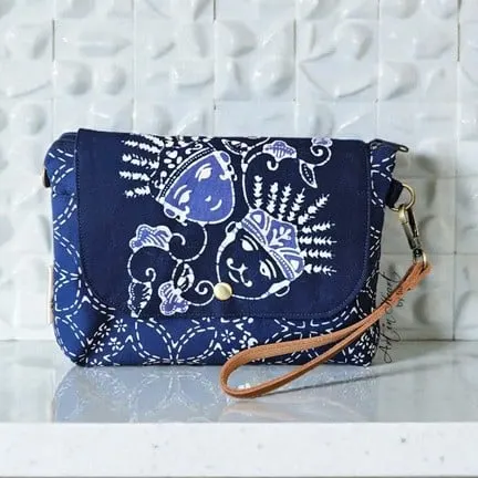 Clutch batik biru tua bertutup lipat dengan motif ondel-ondel dan tali pergelangan cokelat