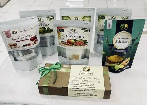 Pouch teh AstuRani Bunga Apel, Guaveera dan Teh Rempah di samping kotak Signature Tea Series berpita hijau