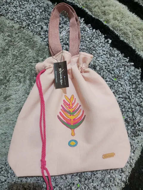 Tas serut kain merah muda bertali pink dengan bordir motif daun warna-warni dan label gantung hitam