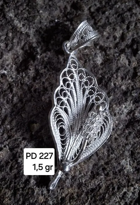 Liontin perak filigree berbentuk daun dengan pola kawat halus di atas batu gelap, berlabel PD 227 1,5 gr