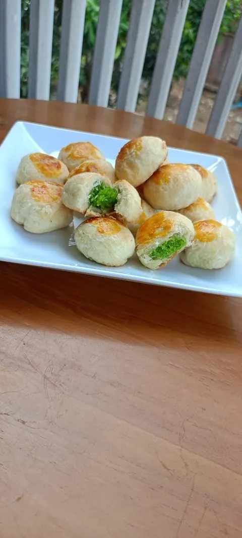 Bakpia bulat di piring putih, dua di antaranya terbelah dan memperlihatkan isian berwarna hijau