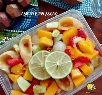 Asinan buah berisi potongan mangga, jambu dan buah lain dengan irisan jeruk nipis dalam wadah plastik