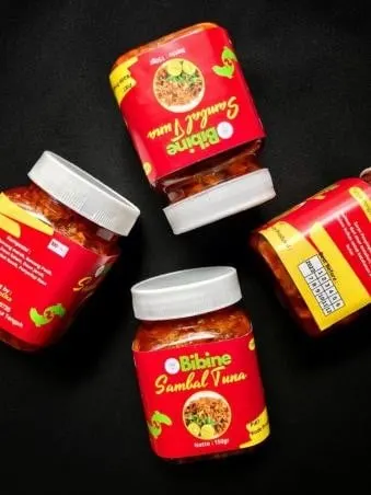 Empat toples plastik Sambal Tuna Bibine berlabel merah dan bertutup putih di atas latar hitam