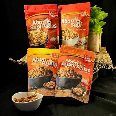 Empat kemasan pouch Bonwie, yaitu Abon Sapi Pedas, Abon Sapi, Abon Ayam, dan Abon Ayam Pedas, dengan semangkuk abon
