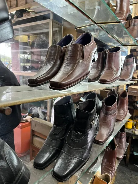 Rak kaca toko berisi deretan sepatu kulit pria warna cokelat dan hitam