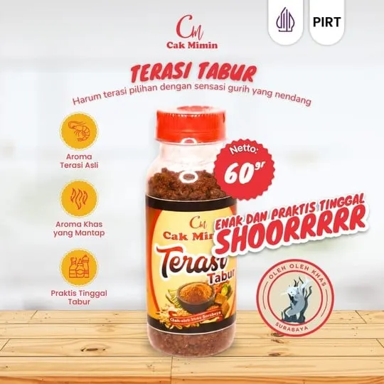 Botol plastik Terasi Tabur Cak Mimin bertutup merah berisi terasi kering di atas meja kayu
