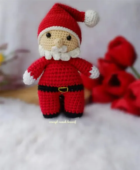Boneka rajut Santa Claus berbaju merah dengan janggut putih di atas bulu putih