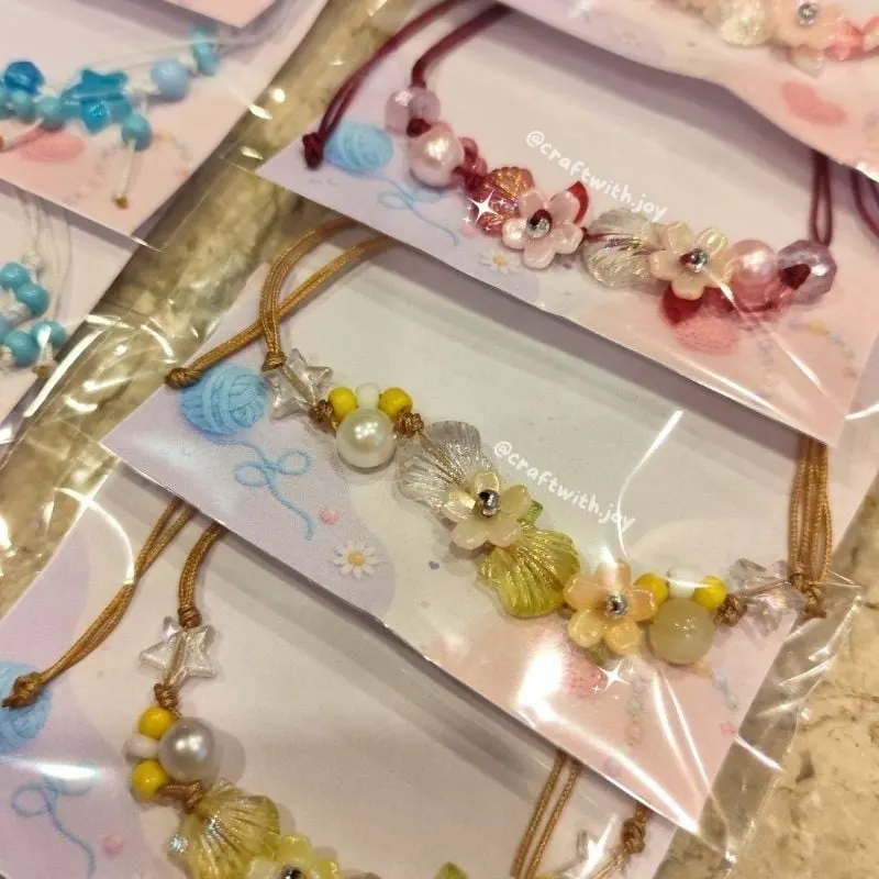 Beberapa gelang tali dengan manik mutiara, bunga dan bintang dalam kemasan plastik berkartu