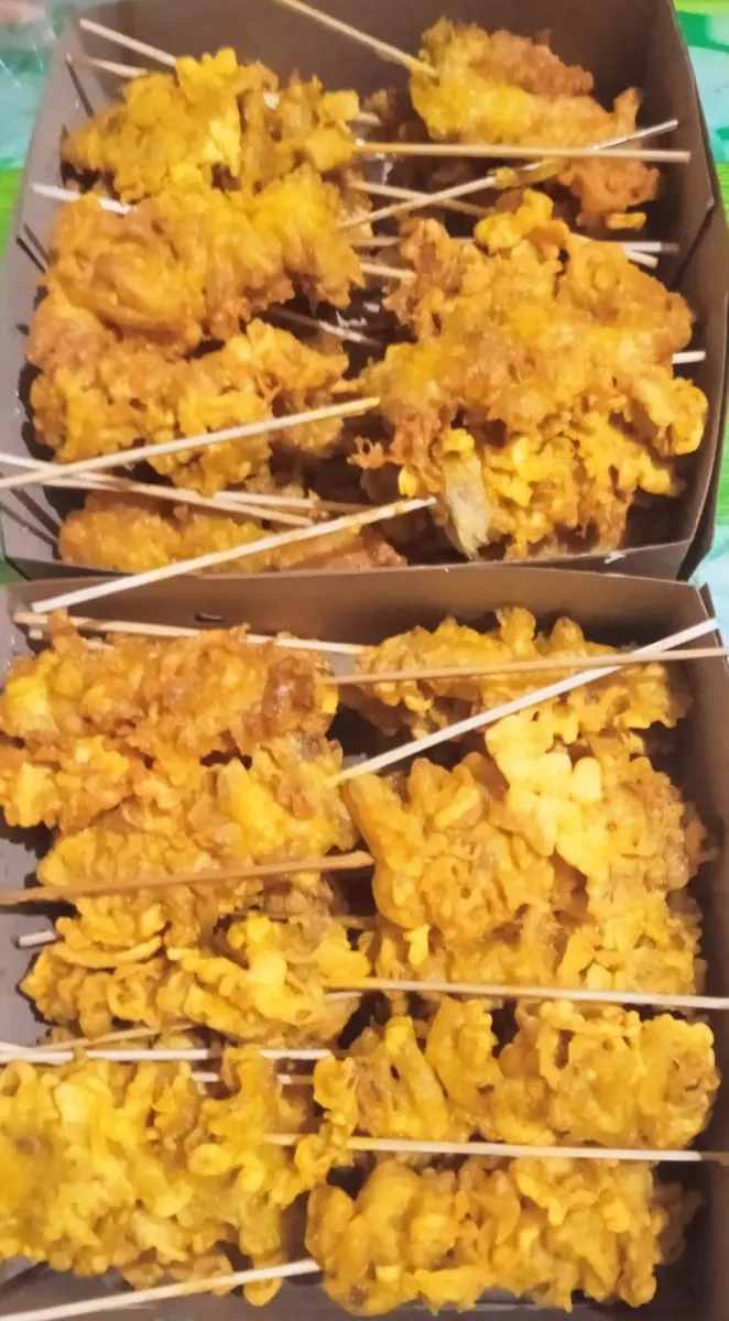Dua kotak kertas berisi sate jamur tiram goreng tepung berwarna kuning keemasan