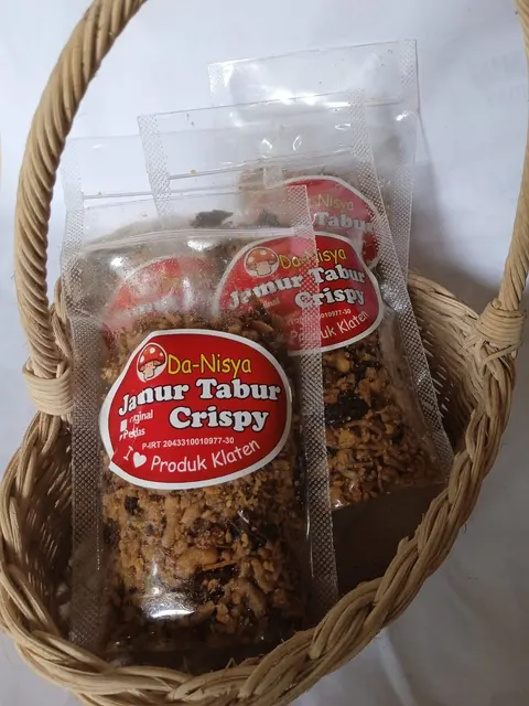 Kemasan plastik Da-Nisya Jamur Tabur Crispy berlabel merah di dalam keranjang rotan