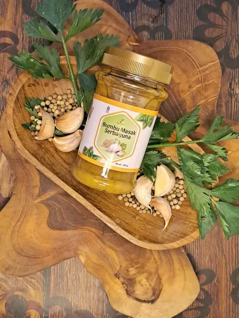 Toples kaca Bumbu Masak Serbaguna 200 g bertutup emas di nampan kayu dengan bawang putih, lada, dan seledri