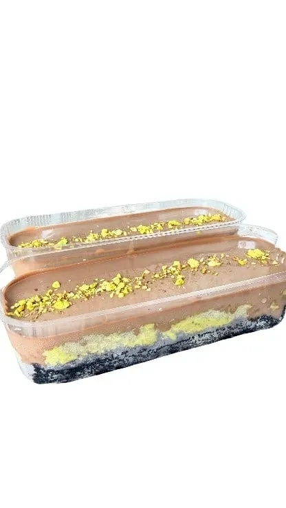 Dua wadah plastik panjang berisi dessert cokelat berlapis dengan taburan remah kuning kehijauan