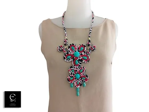Kalung besar dari gulungan kain batik merah hitam dengan manik toska dipakai manekin bergaun krem