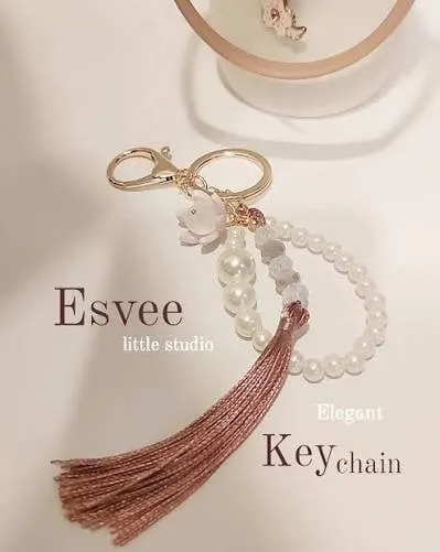 Gantungan kunci manik mutiara dengan bunga merah muda dan rumbai cokelat, bertuliskan Esvee Elegant Keychain