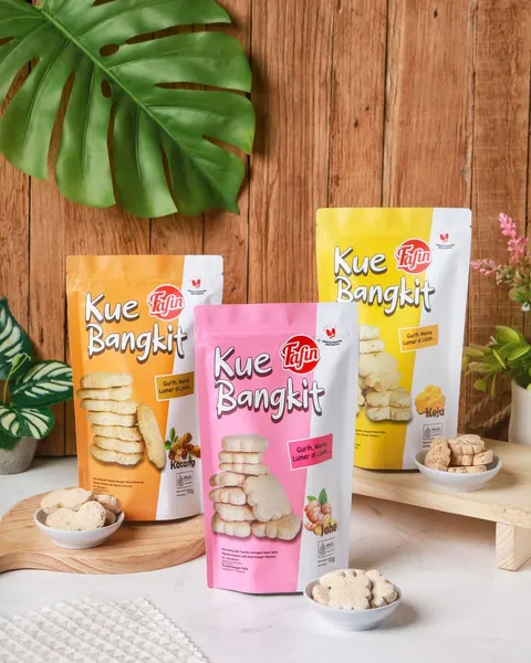 Tiga pouch Kue Bangkit Fafin rasa kacang, jahe dan keju dengan mangkuk berisi kue di depan dinding kayu