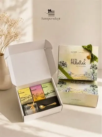 Kotak hampers Eid Mubarak berpita hijau berisi tiga kemasan teh warna-warni, gelas kecil dan sendok emas