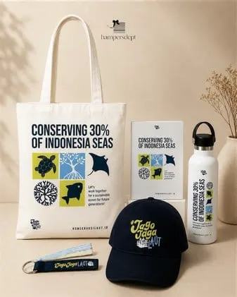 Merchandise tema laut berupa tote bag, botol minum, topi hitam dan gantungan kunci di latar krem