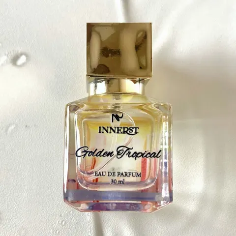 Botol parfum kaca kotak Innerst Golden Tropical 30 ml bertutup emas di atas kain putih