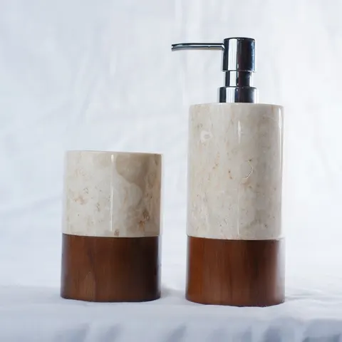 Dispenser sabun dan gelas dari marmer krem dengan bagian bawah kayu jati di atas kain putih