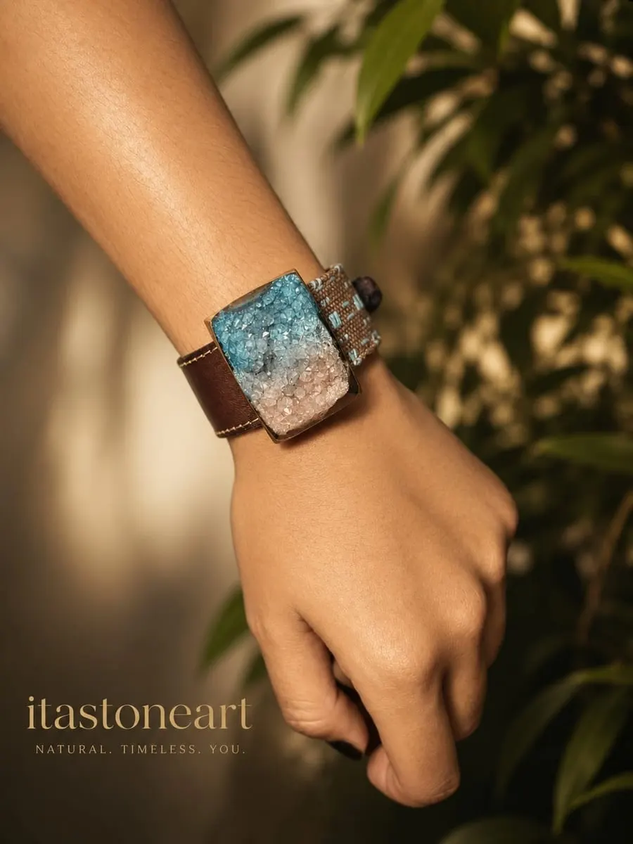 Gelang kulit cokelat dengan lempeng berisi pecahan kristal biru dan merah muda dipakai di pergelangan tangan