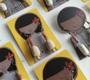 Anting manik-manik pada kartu kuning bergambar anak perempuan berambut hitam dengan bunga merah