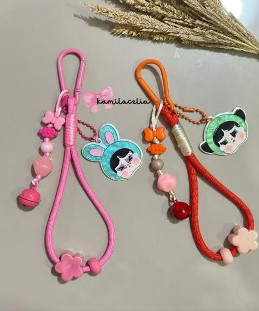 Dua phone strap tali merah muda dan oranye dengan hiasan manik dan gantungan wajah kartun