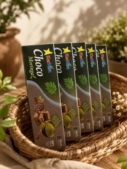 Lima kotak hijau tua cokelat KarNisa Choco Moringa berjajar dalam keranjang rotan
