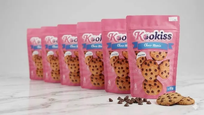 Enam pouch merah muda Kookiss Choco Mania berjajar di meja marmer dengan cookies dan chocochips