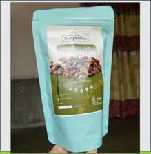 Tangan memegang pouch biru muda berlabel hijau Kopiku Mix Coffee bergambar biji kopi sangrai