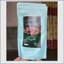 Tangan memegang pouch biru muda berlabel hijau tua Kopiku Robusta Gayo bergambar biji kopi sangrai