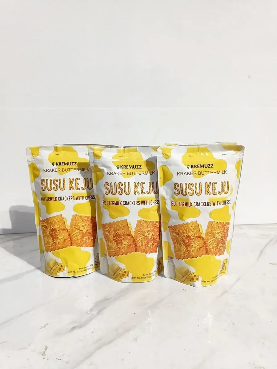 Tiga kemasan pouch Kremuzz Susu Keju kuning putih berjajar di atas meja marmer