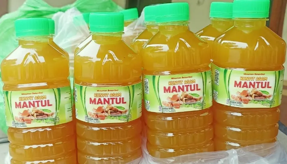 Empat botol plastik kunyit asam Mantul bertutup hijau berisi minuman kuning jingga dengan label hijau