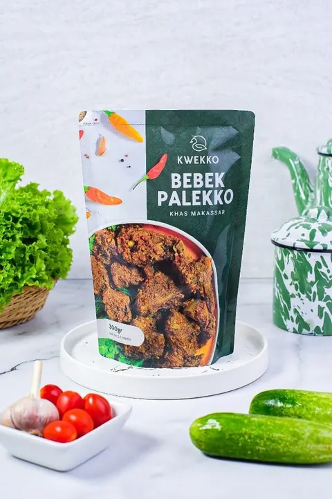 Kemasan pouch hijau Bebek Palekko Kwekko 300 gr di atas nampan putih, dikelilingi selada, tomat, dan timun