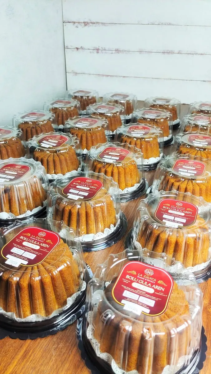 Deretan bolu dalam mika bening berlabel merah La Zalyca Bolu Gula Aren Original di meja kayu