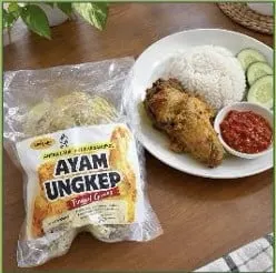 Kemasan plastik Ayam Ungkep di samping piring berisi nasi putih, ayam goreng, sambal dan irisan timun