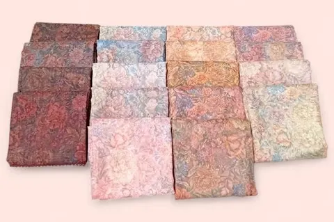 Dua belas hijab terlipat bermotif bunga bernuansa cokelat, merah muda dan biru di atas latar terang