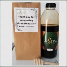 Botol plastik madu Lusera 1 kg di samping kantong kertas cokelat bertuliskan ucapan terima kasih dan sendok madu kayu