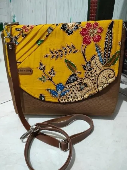 Tas selempang dengan tutup kain batik kuning bermotif bunga dan tali kulit cokelat