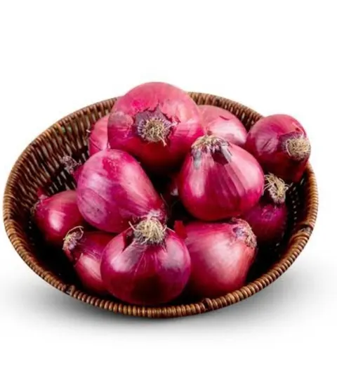 Bawang merah utuh berkulit ungu kemerahan dalam keranjang anyaman cokelat di atas latar putih
