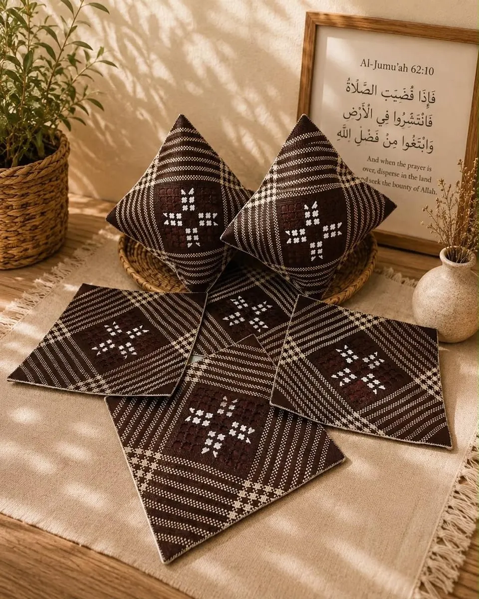 Dua bantal dan empat sarung bantal persegi anyaman pandan cokelat tua bermotif bunga putih di atas kain krem