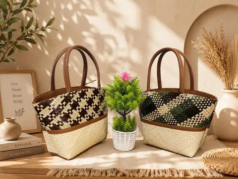 Dua tas jinjing anyaman pandan bermotif kotak hitam krem dan hijau tua dengan gagang cokelat di atas meja