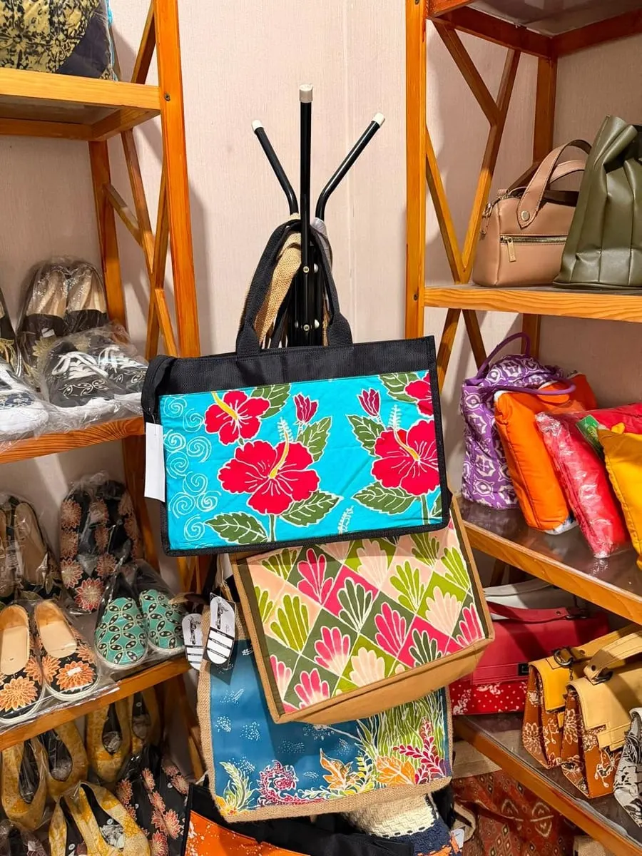 Tas jinjing berpanel batik motif kembang sepatu merah tergantung di antara rak sepatu dan tas