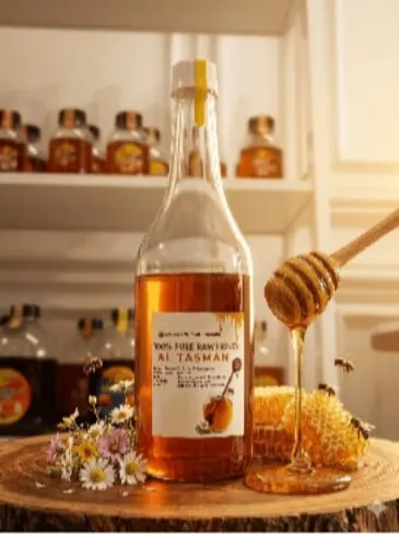 Botol kaca madu berlabel 100% Pure Raw Honey Al Tasman di samping sarang lebah dan sendok madu