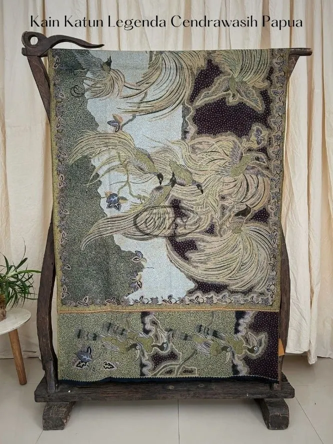 Kain batik bermotif burung cendrawasih warna hijau keabuan dan cokelat tergantung di gawangan kayu