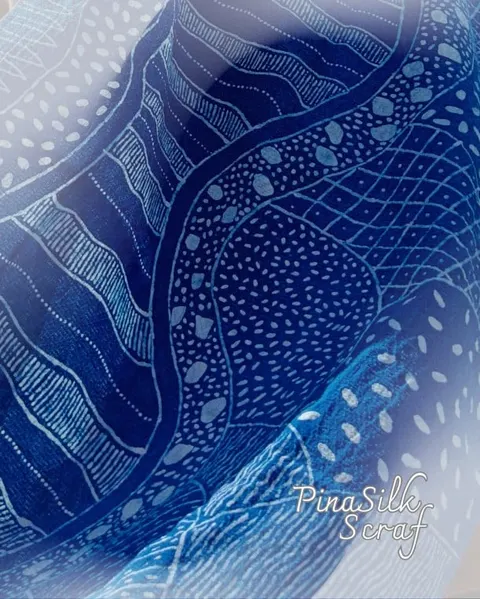 Scarf biru tua bermotif garis, titik dan lengkung putih dengan tulisan PinaSilk Scraf