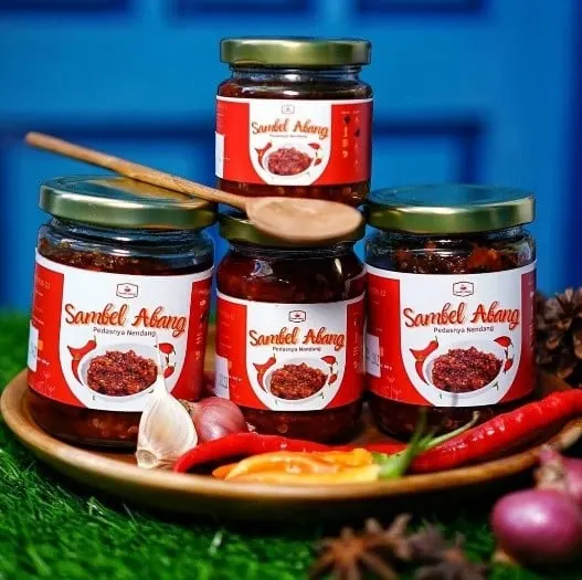 Empat toples Sambel Abang berlabel merah di atas nampan kayu dengan cabai, bawang dan sendok kayu