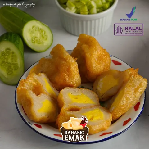Potongan pempek goreng berisi kuning telur di piring enamel bermotif merah, dengan irisan timun